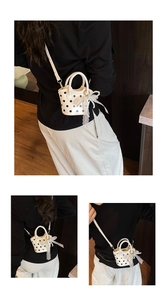 Close-up of mini white polka dot bucket bag with lace bow and pearl pendant details