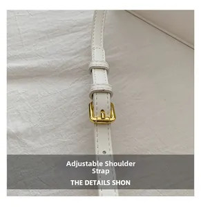 Close-up of white leather adjustable shoulder strap with refined gold metal buckle hardware