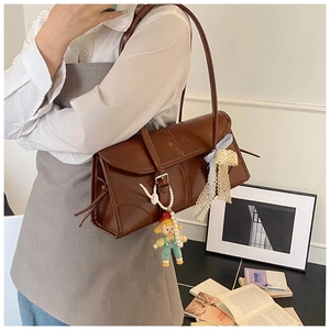 Detail of a brown vintage leather tote bag featuring a cute doll and lace bow accessory