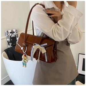 Detail of vintage brown leather tote bag with lace bow and cute doll charm pendant