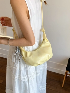 Minimalist light yellow leather crescent bag with starfish pendant on white dress