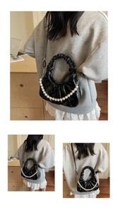 Detail of black ruched crescent bag with large pearl handle and adjustable strap