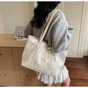 Vista laterale della borsa tote crema con stampe a farfalla e dettagli in pizzo