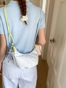 Minimalist white croissant half-moon shoulder bag with yellow strap and dog charm