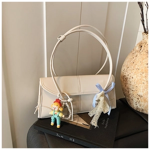 Detail of cream shoulder bag with cartoon doll pendant and blue checkered lace ribbon