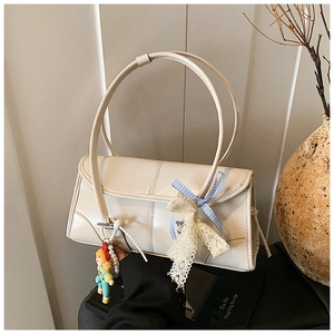 Detail of cream white baguette bag with lace ribbon, plaid bow and pearl chain charm