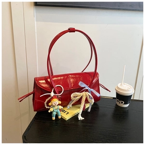Detail of red patent leather tote bag featuring lace bows and a cute doll pendant