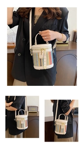Detail of colorful striped straw bucket bag with cream leather strap and handles