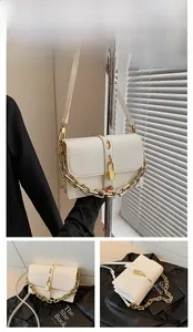 Detail showing white PU crossbody bag with chunky metal chain and golden locket charm