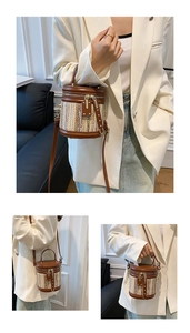Detailed view of handwoven bucket bag with brown leather trim and golden hardware rivets