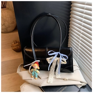 Detail of black glossy shoulder bag featuring blue plaid bows and a cute doll pendant