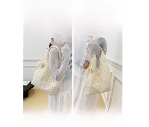 Detail of white mesh tote bag featuring delicate daisy embroidery and a floral pendant