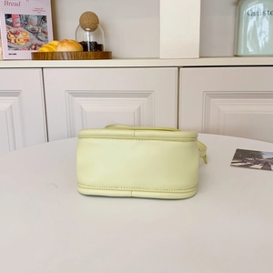 Minimalist cream yellow leather handbag with refined bottom stitching in a lifestyle setting