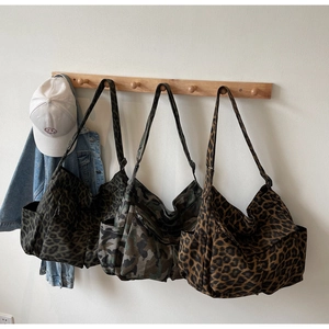 Detailed display of leopard and camo canvas bags with side pockets and wide straps