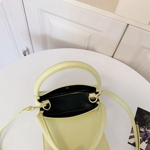 Top view of a minimalist light yellow small square handbag with golden metal hardware