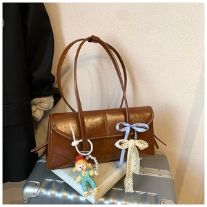 Detail of vintage brown tote bag with blue plaid bow and pearl doll pendant charm
