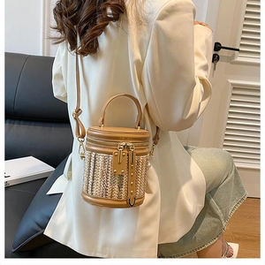 Détail d'un sac seau tressé avec garniture en cuir, finitions dorées et fermeture éclair