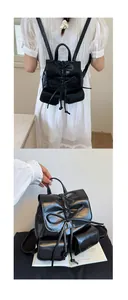 Detail of black glossy mini backpack with bow decoration and drawstring texture