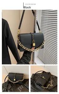 Detail of black crossbody bag with decorative gold chain and small padlock hardware