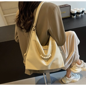 Detail of off-white lychee texture tote bag with elegant gold and pearl chain strap