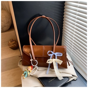 Brown vintage tote bag with blue plaid bow and cute plush doll detail on blazer background