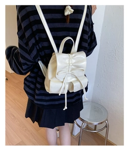 Rear view of a white bow-knot mini backpack with ruffle details and drawstring closure