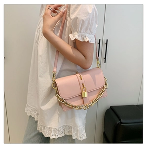Detail of pink messenger bag with bold gold chain and decorative lock pendant