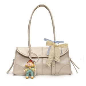 Detail of cream tote bag featuring a blue plaid bow and cute cartoon girl charm