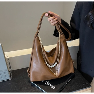 Close-up of brown faux leather tote bag with elegant pearl and gold chain strap detail