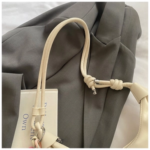 Detail of cream leather bag strap with stylish knots and metallic cylinder ends on a suit
