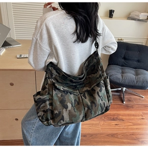 Detail of camouflaged canvas crossbody bag showing jungle pattern and adjustable strap