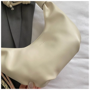 Detail of off-white dumpling bag with knot handle and embossed brand logo dimrab