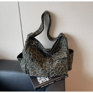 Detail of leopard print canvas crossbody bag with multiple utility pockets and wide strap
