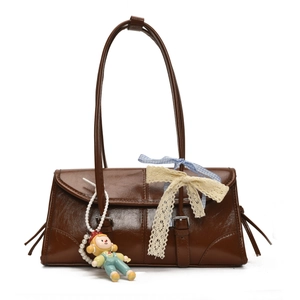 Detail of vintage brown glossy leather tote featuring decorative buckles and a pearl charm