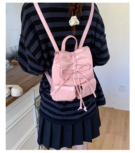 Detail of pink bow and pleated drawstring on a glossy faux leather backpack back view