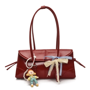 Detail of red patent leather tote bag with clown charm and lace bow decoration