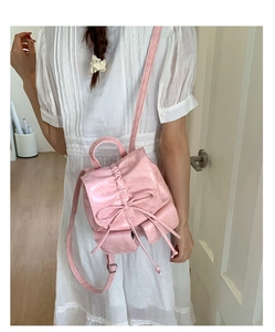 Detailed view of pink bow backpack with drawstring closure and glossy PU leather texture