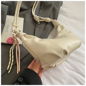 Detail of off-white dumpling bag with pleated leather texture and heart charm pendant