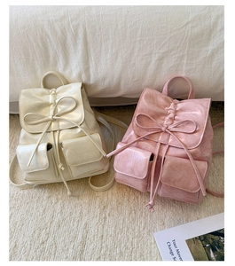 Detail of cream white and pink bow drawstring backpacks in soft pleated faux leather