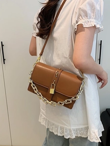 Stylish brown crossbody bag with gold chain and padlock detail on shoulder model