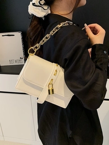 Fashionable white crossbody bag with chunky gold chain strap worn on black shirt