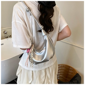 Silver crescent hobo bag with knotted strap and heart charm detail on a model