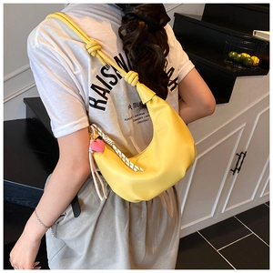 Detail of yellow crescent hobo bag with knotted strap and pink heart pendant charm