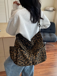 Large capacity leopard print canvas shoulder bag with multiple pockets worn by a model