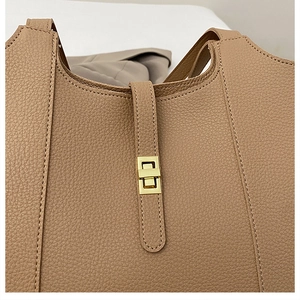Close-up of litchi grain leather texture and golden metal swivel lock on the handbag