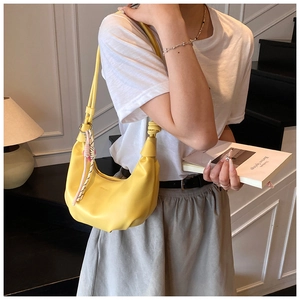 Detail of yellow crescent hobo bag with a knotted handle and silk scarf accessory