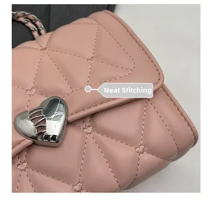 Gros plan sur les coutures soignées et la boucle argentée en forme de cœur du sac rose