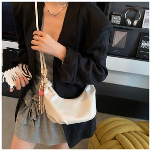 Creamy white crescent shoulder bag with pleated detail and a pink heart charm