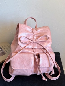 Pink drawstring backpack with bow detail and twin front pockets in soft textured finish