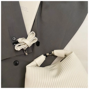 Détail du sac à main blanc plissé avec boucles argentées et bandoulière amovible
